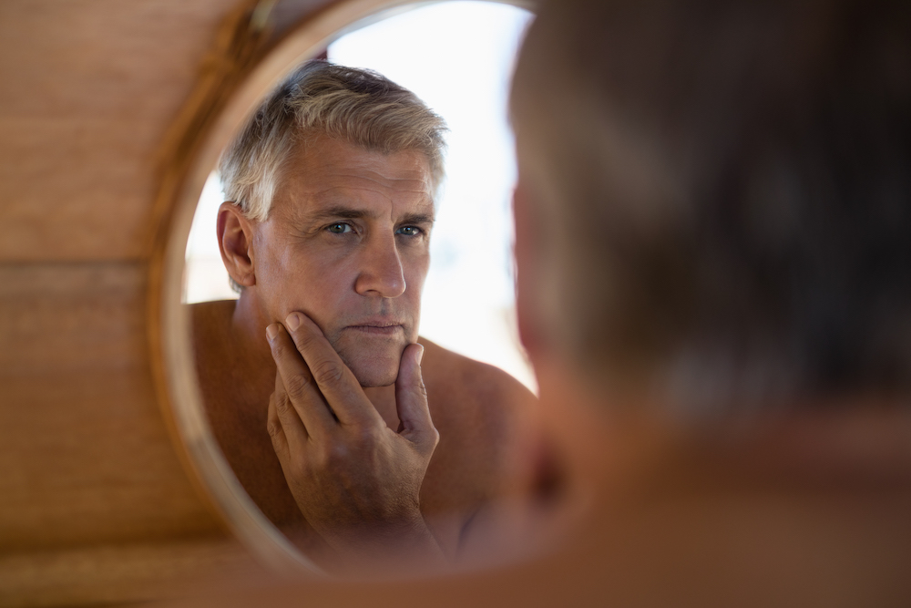 mature man looking at himself in the mirror