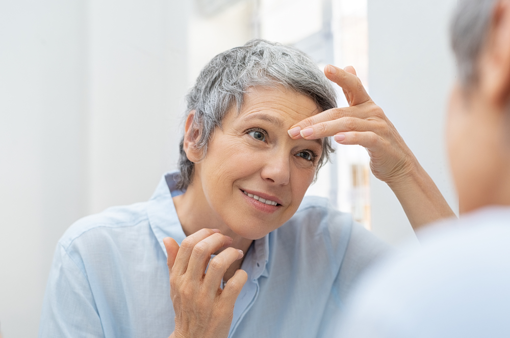 mature woman looking at her reflection before anti wrinkle injections in Sterling Heights