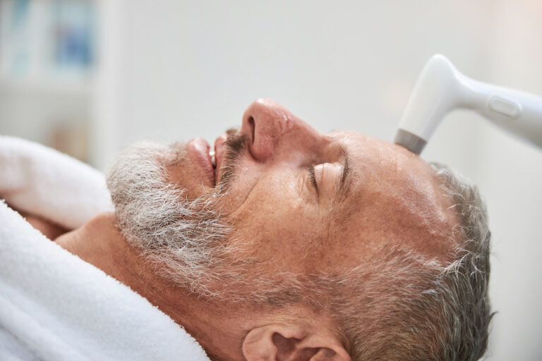 A mature man smiles during a laser skin damage treatment in Sterling Heights