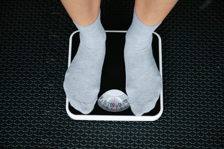 Close up of a person wearing gray socks standing on a scale at our Weight Loss Clinic near Macomb, MI.
