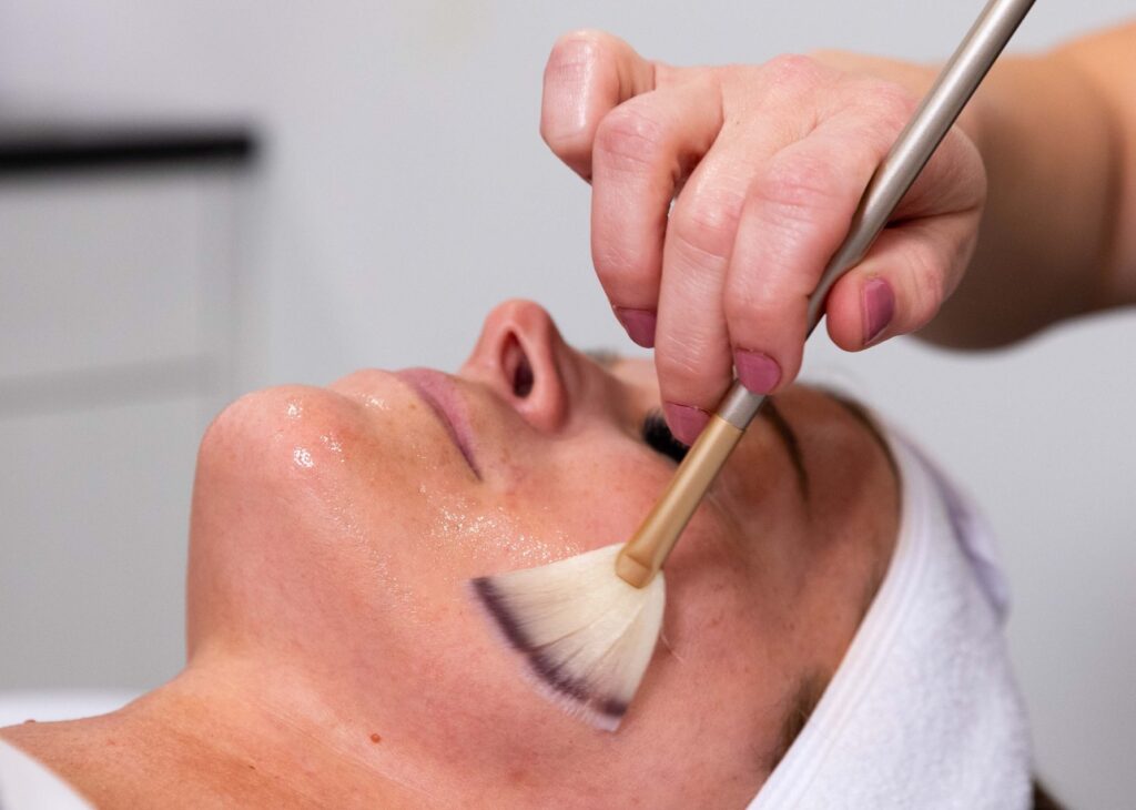 Close up of a woman recieving a chemical peel at a Facial Med Spa Near Shelby Township, which is being applied by brush to her cheek.